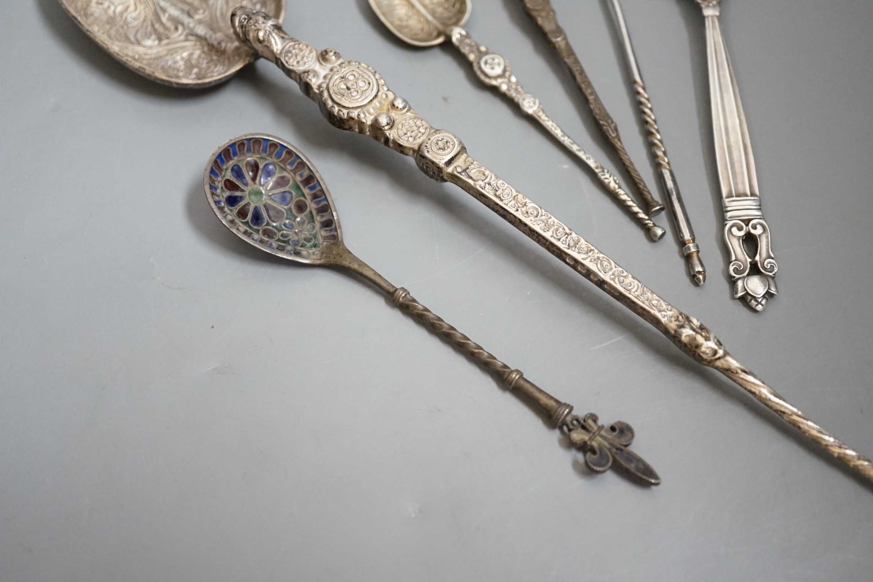 A 1930's silver replica of The Anointing spoon, 24.7cm, two similar smaller spoons, a Georg Jensen spoon, an Austro-Hungarian white metal and plique a jour spoon and a Russian tea spoon.